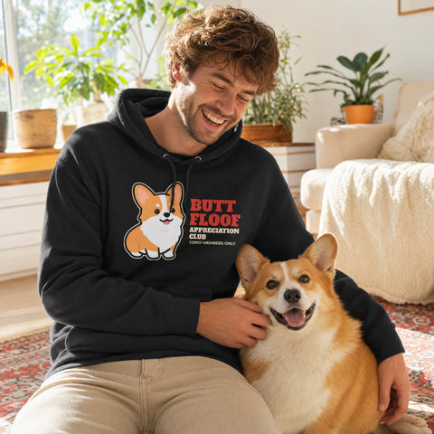 Man laughing in a black Butt Floof Appreciation Club corgi hoodie, petting his Pembroke Welsh corgi - funny corgi gift for dog dads