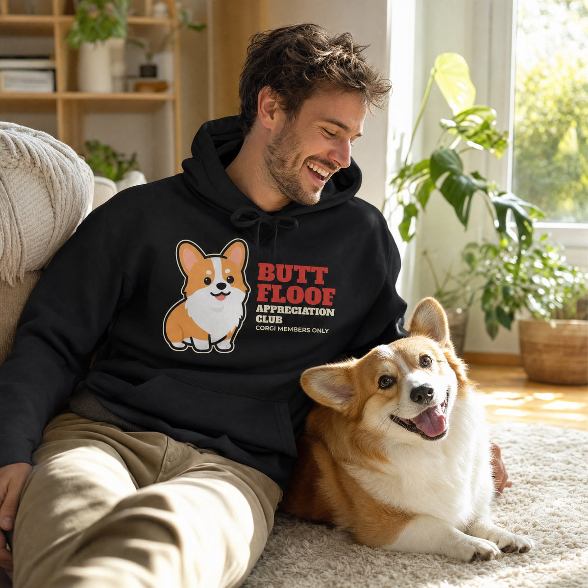 Funny corgi hoodie for humans worn by a corgi owner relaxing at home with his dog - cute gift for corgi lovers