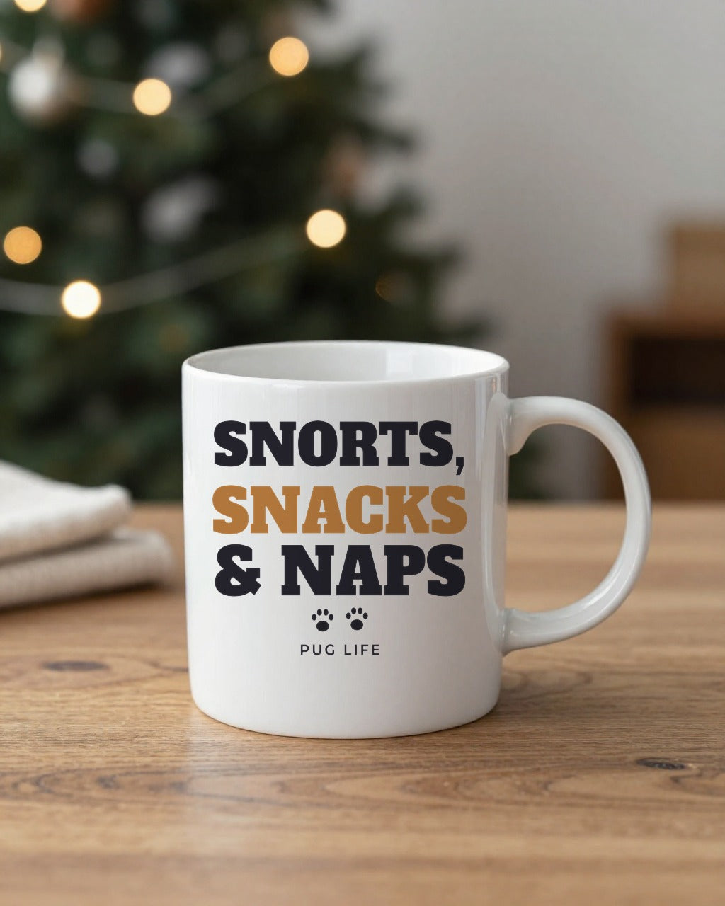 Snorts Snacks and Naps pug mug on a table by a Christmas tree