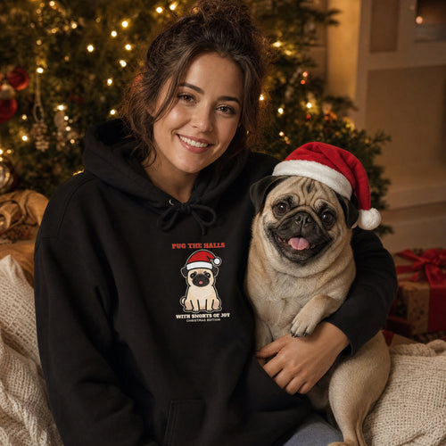Pug mom in a black Pug the Halls Christmas hoodie hugging her pug in a Santa hat by the Christmas tree - funny pug Christmas gift