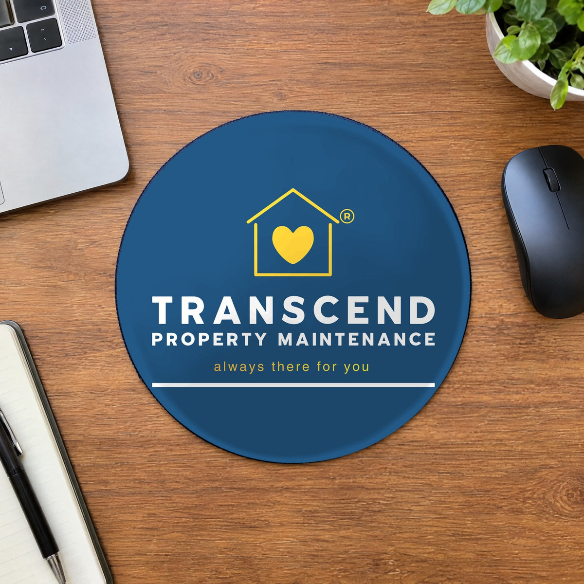 Transcend Property Maintenance round mouse pad on an office desk (AI-generated example scene, artwork placed from the real design)