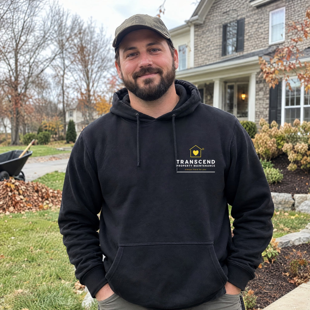 Landscaper wearing the Transcend Property Maintenance black hoodie with the logo on the left chest (AI-generated example photo, logo placement matched to the real product)