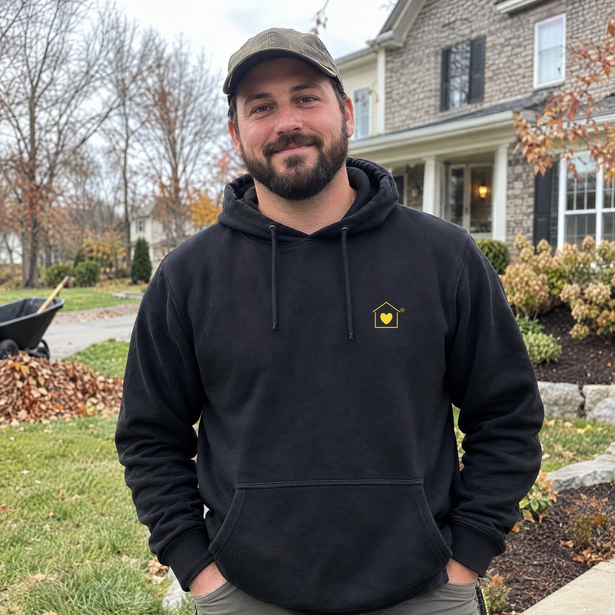 Landscaper wearing the Transcend Icon Edition black hoodie with the house-and-heart icon on the left chest (AI-generated example photo, logo placement matched to the real product)