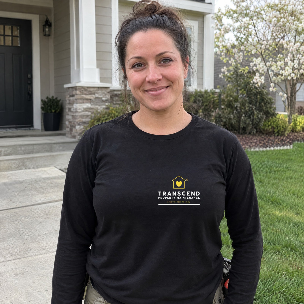 Property maintenance worker wearing the Transcend Property Maintenance black long sleeve tee with the logo on the left chest (AI-generated example photo, logo placement matched to the real product)