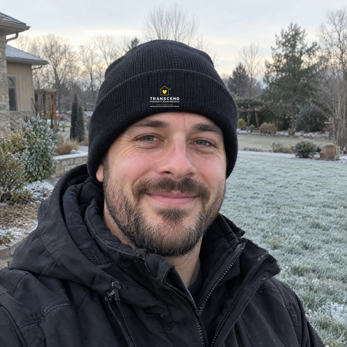 Landscaper wearing the Transcend Property Maintenance black winter beanie with the logo on the cuff (AI-generated example photo, logo size and placement matched to the real product)