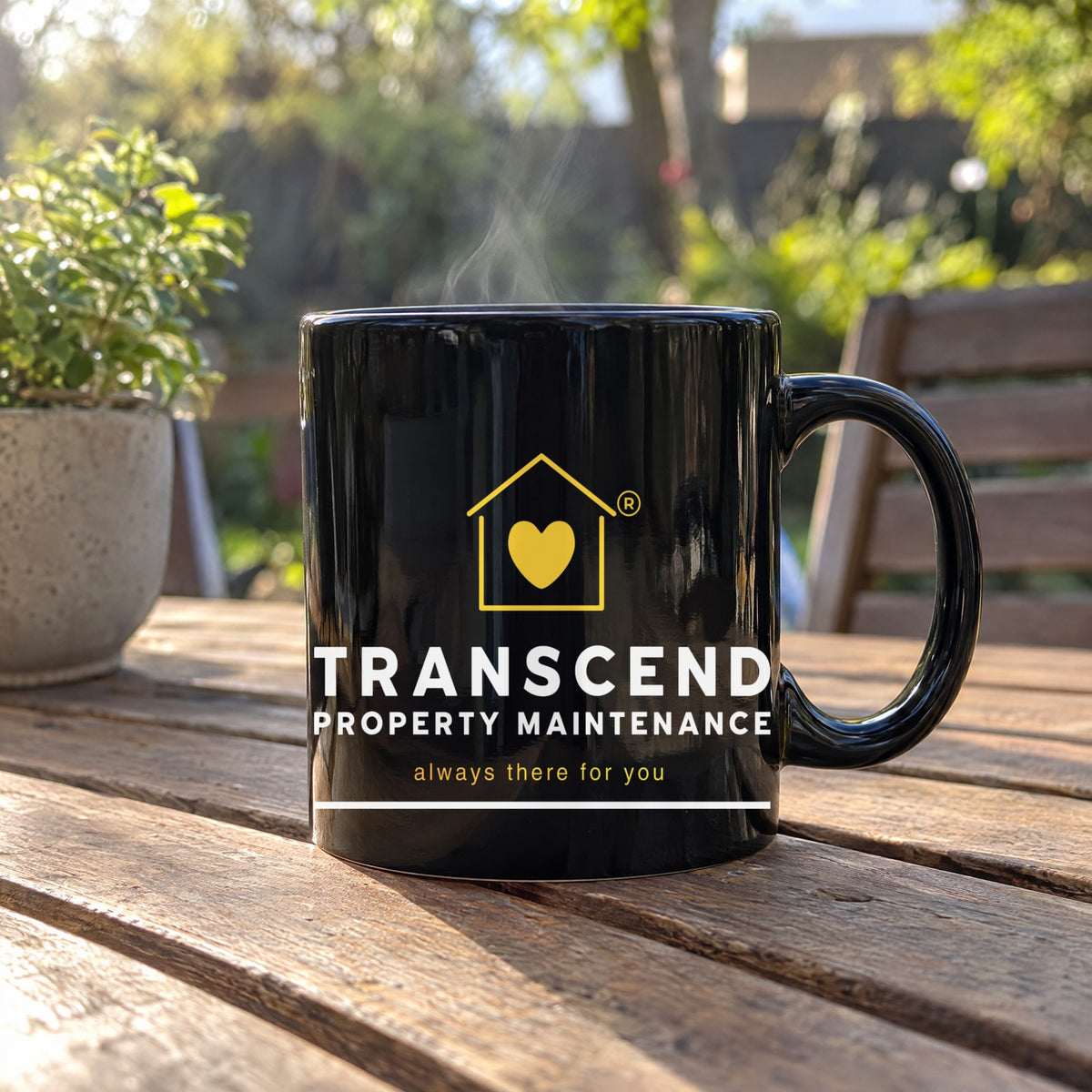 Transcend Property Maintenance black coffee mug on a sunny patio table (AI-generated example photo, logo size and placement matched to the real product)